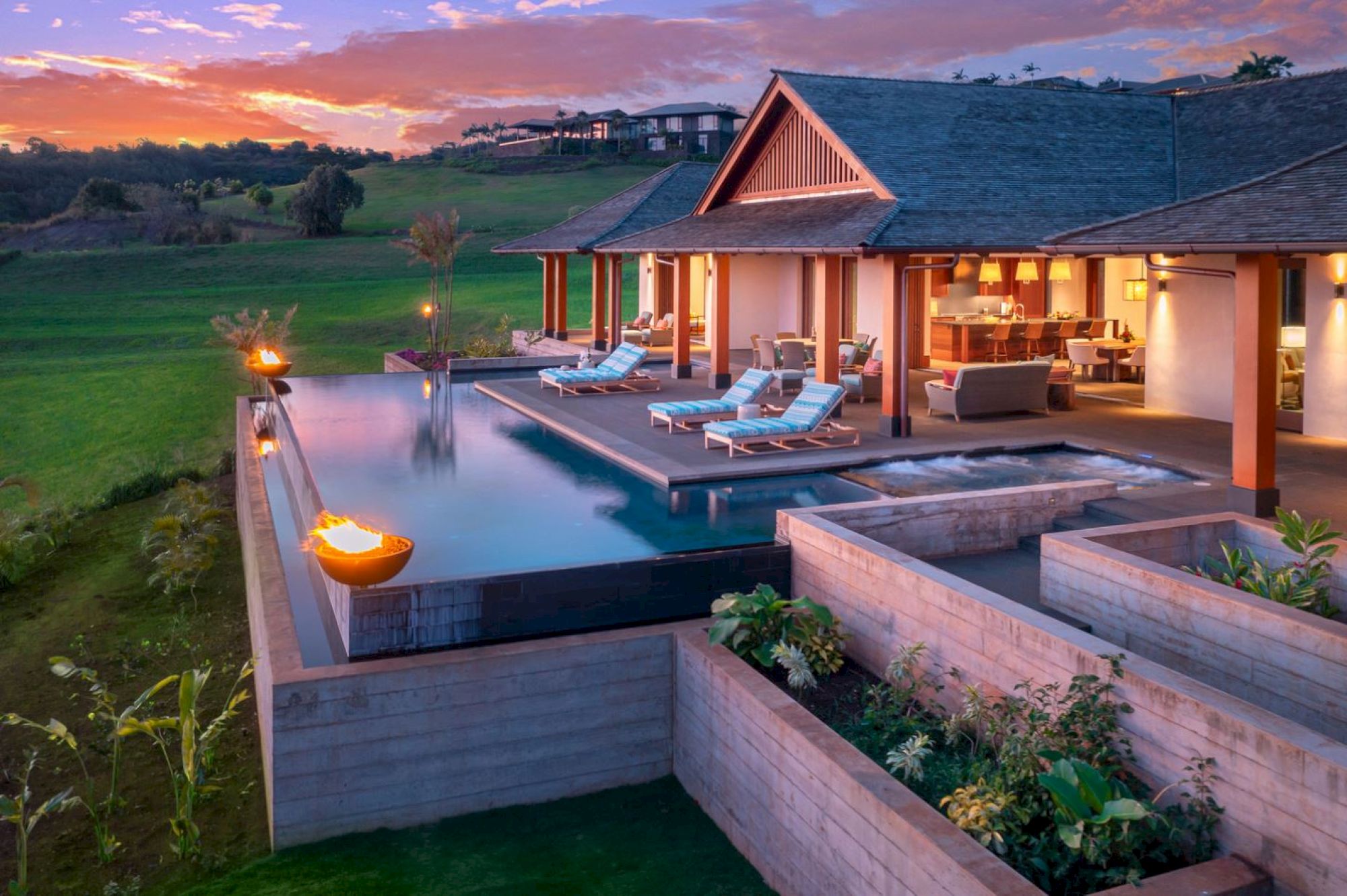 The image features a luxurious villa with an infinity pool, surrounded by greenery and a beautiful sunset in the background.