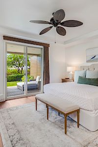 A stylish bedroom featuring a large bed, bedside tables, a chair, a TV, and sliding doors leading to an outdoor area.