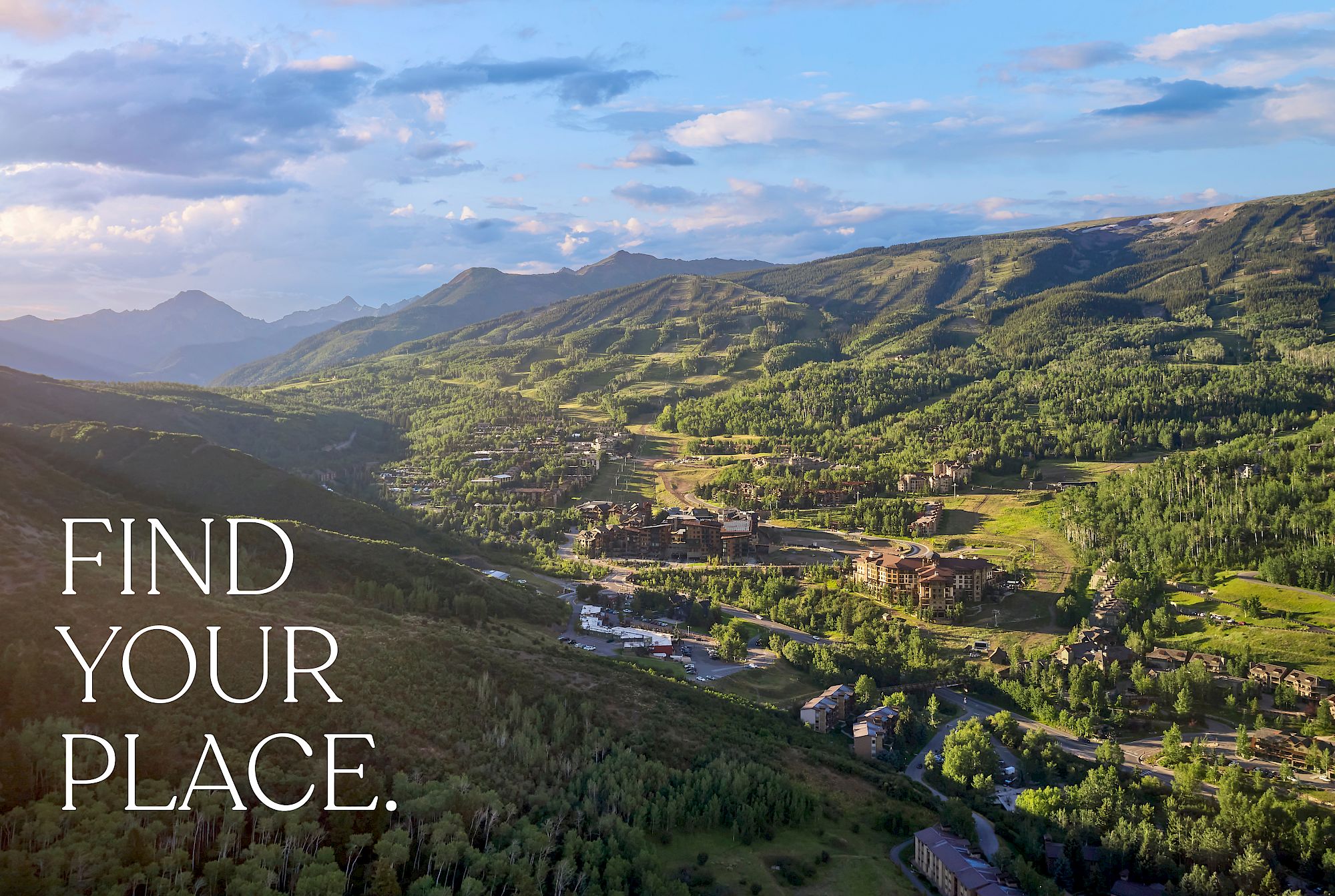 A scenic view of a mountainous landscape with lush greenery, buildings, and the text "FIND YOUR PLACE." on the left side of the image.