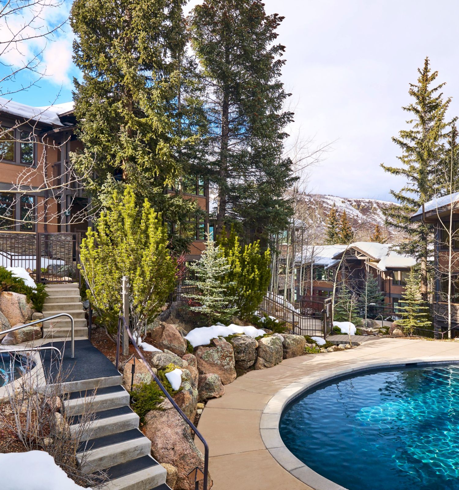 The image features a serene landscape with a pool area, snow, trees, and modern buildings, creating a tranquil retreat vibe.