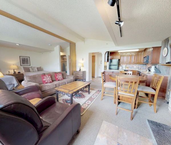 The image shows a cozy living space with a sofa, dining area, kitchen, and decorative elements for a warm atmosphere.