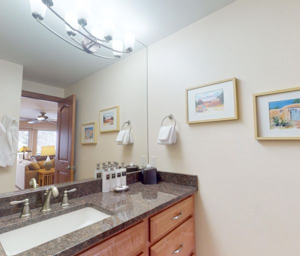 The image shows a stylish bathroom with a sink, towels, and framed artwork on the wall, reflecting a cozy atmosphere.