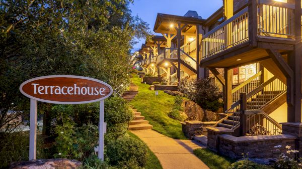 The image features a cozy residential building with a sign reading "Terracehouse," illuminated stairs, and lush greenery.